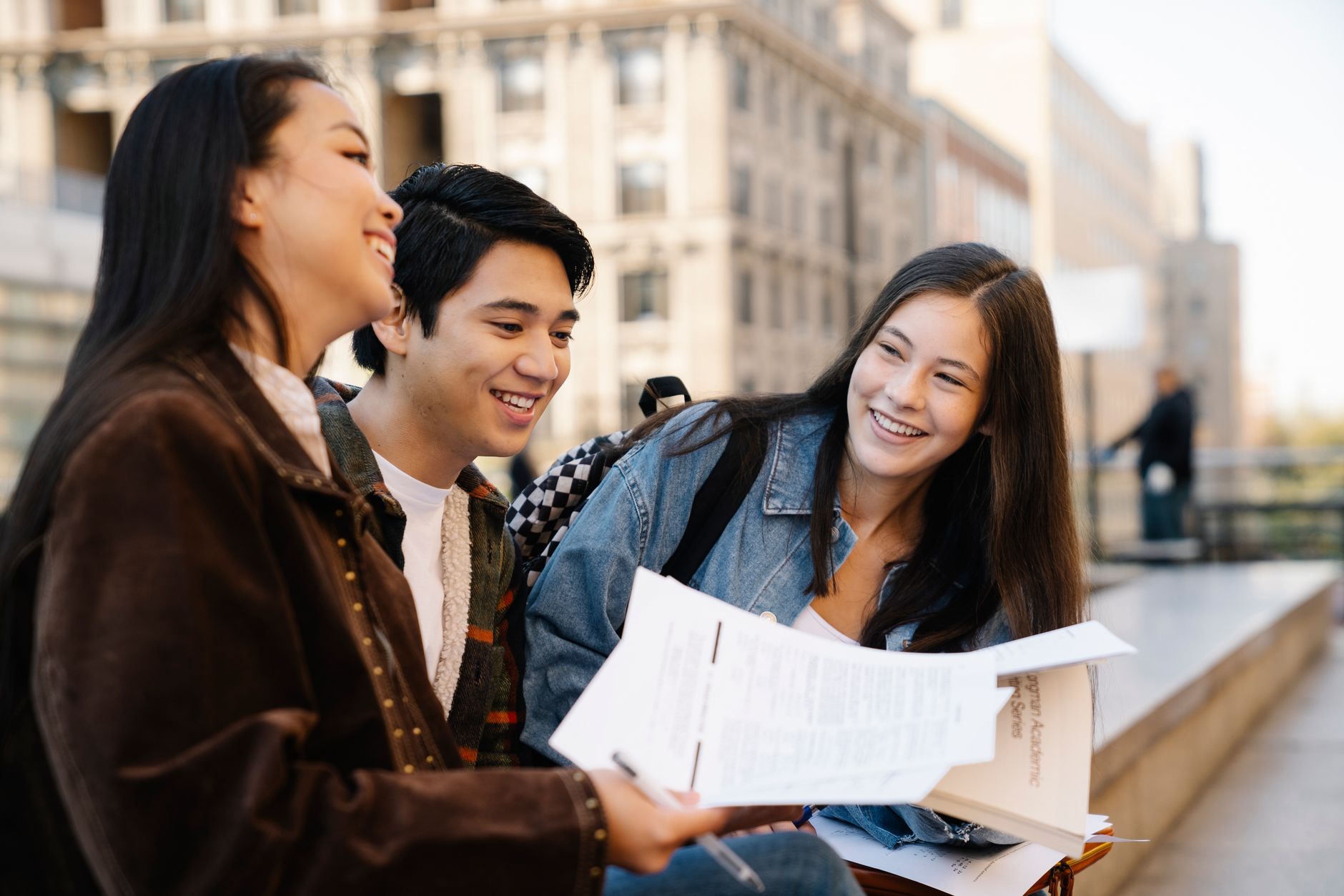 Trois jeunes adultes assis sur des bancs sur le campus, profitant de leur conversation.